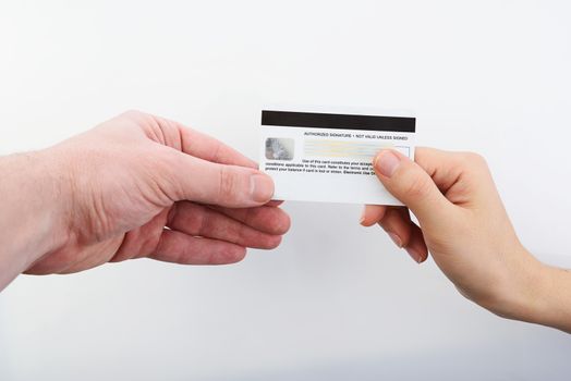 One hand gives credit card to other hand on white background