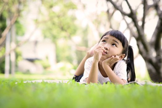 Asian kid thinking while playing in the garden