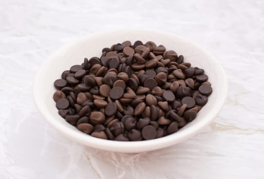 China dish of milk and dark chocolate chips on a kitchen work surface