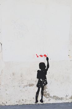 Graffiti of boy drawing animals on white wall