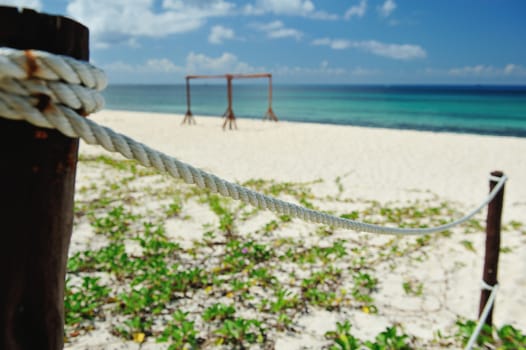 Fence from white rope on blue beach