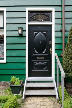 Black wooden vintage door wth green wall house