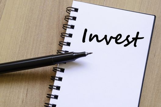 Invest text concept write on notebook with pen
