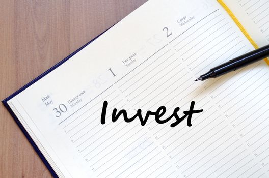 Invest text concept write on notebook with pen