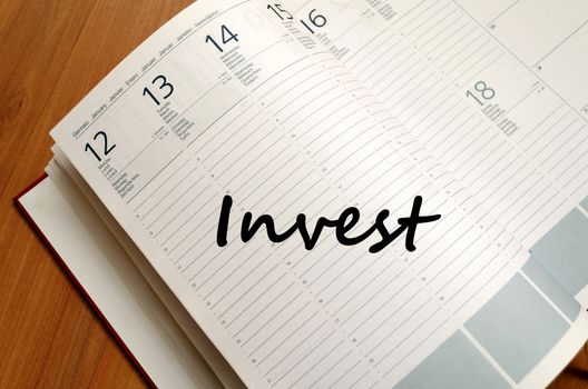 Invest text concept write on notebook with pen