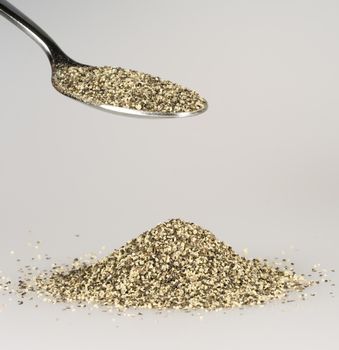 Ground Pepper on Tablespoon with a pile of black pepper beneath.