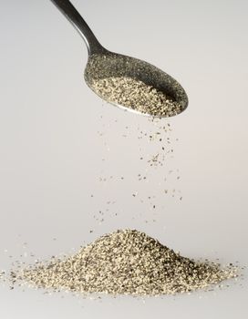 Black Pepper Falling from tablespoon close up.