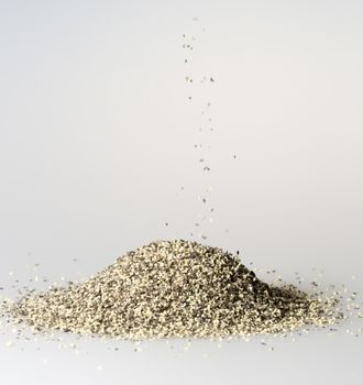 Black Pepper Grains Falling into Pile close up.