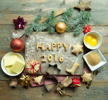 Happy 2016 made from cookies on top of a chopping board with baking ingredients