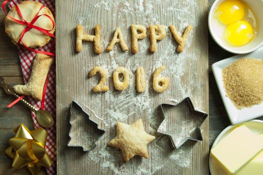 Happy 2016 made from cookies on top of a chopping board with baking ingredients