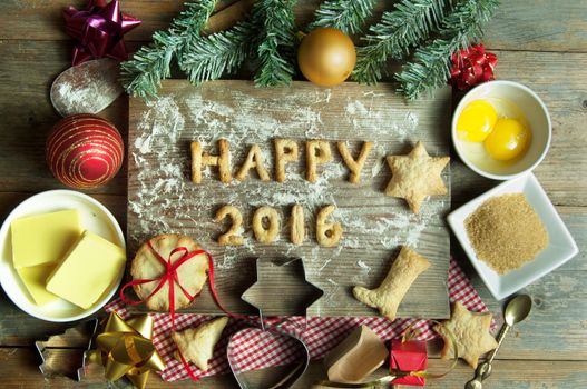 Happy 2016 made from cookies on top of a chopping board with baking ingredients