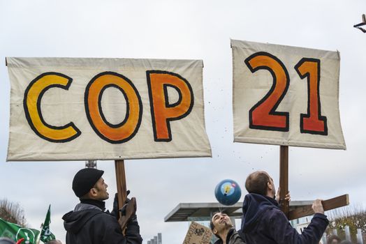 FRANCE, Paris : A couple of demonstrators holds signs reading COP 21 among thousands demanding climate justice and environment protection in Paris on December 12, 2015. A climate march was organized by several NGOs as COP21 negotiations come to an end. 
