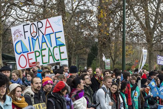 FRANCE, Paris : A demonstrator holds a sign reading For a climate of peace among thousands demanding climate justice and environment protection in Paris on December 12, 2015. A climate march was organized by several NGOs as COP21 negotiations come to an end. 