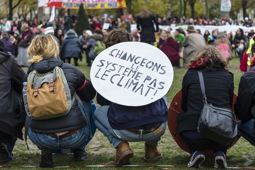 FRANCE, Paris : A demonstrator holds a sign reading Change the system, not the climate among thousands demanding climate justice and environment protection in Paris on December 12, 2015. A climate march was organized by several NGOs as COP21 negotiations come to an end. 