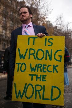 FRANCE, Paris : A demonstrator holds a sign reading It is wrong to wreck the world among thousands demanding climate justice and environment protection in Paris on December 12, 2015. A climate march was organized by several NGOs as COP21 negotiations come to an end. 