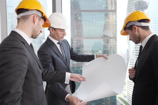 Businessmen and architect team in office planning construction project with office buildings