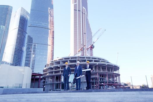 Architects with blueprint at skyscrapers background