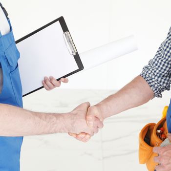 Two construction workers shaking hands, deal is finished concept