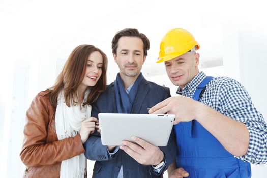 Worker and couple using tablet pc at construction site