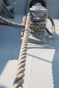 Close up detailed top view of grey nautical rope at an open deck of a ship.