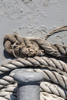 Close up detailed top view of grey nautical rope at an open deck of a ship.