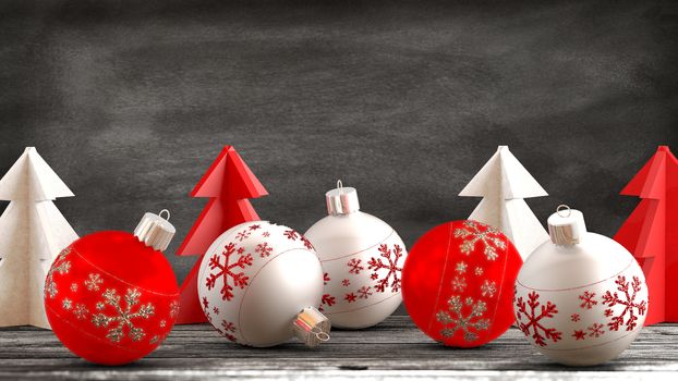 Christmas ornaments, balls, paper trees on a wooden table in front of a blackboard background. Copy space available.
