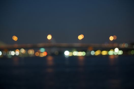 Defocused of glitter or colorful bokeh circle from bridge over river at night as background.