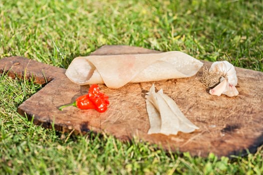 Pig skin slices, garlic and pepper on wooden plate