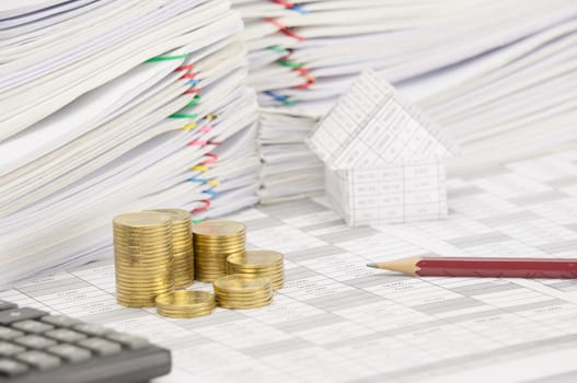 Step pile of gold coins and pencil on finance account have blur calculator and house with pile of document as foreground and background.