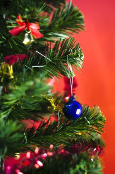 close up blue christmas ball on tree on red background