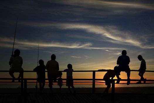 Children playing at the beach in silhouette with sunset background