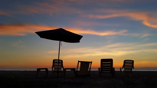 Silhouette seat at the beach front in blurry sunset background