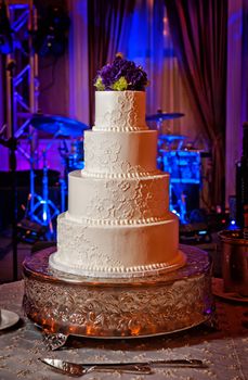 Image of an elegant cream wedding cake with purple flower topper