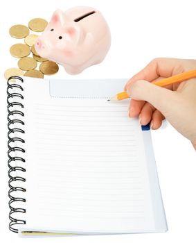 Females hand writing in notebook and piggy bank on isolated white background