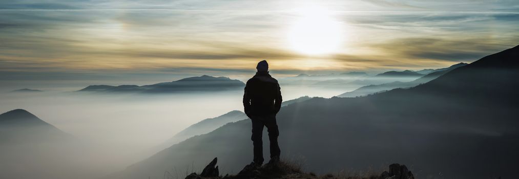 Man watching mountains clouds from a peak in the Alps