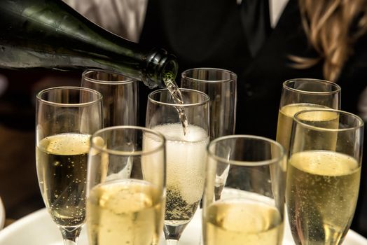 Image of a waitress filling glasses with champagne