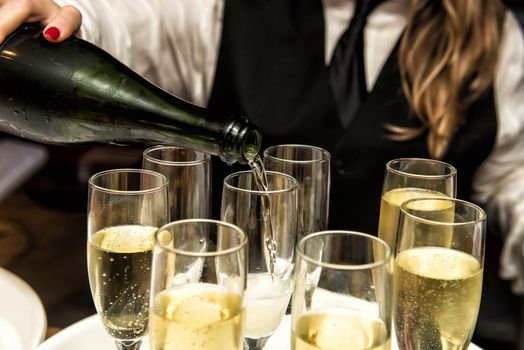 Image of a waitress filling glasses with champagne