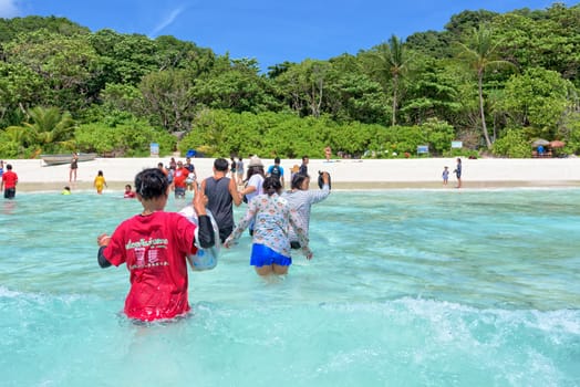 PHANG NGA, THAILAND - MAY 1, 2015: Tourists arriving by boat are to walk through the waves of the blue sea to the beach of Similan Islands during the summer at Mu Ko Similan National Park