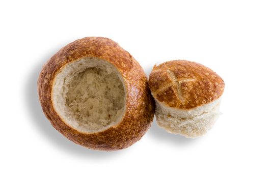 Crusty fresh sourdough roll prepared as a bread bowl for soup with the cap lying alongside, overhead view on white with copy space