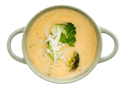 Bowl of tasty cream of broccoli soup garnished with fresh parsley and grated cheddar cheese, overhead view isolated on white
