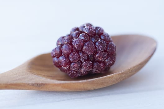Close-up of a blackberry in a spoon on a table