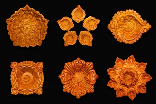 Top view Collage of beautifully carved designer different types of handmade clay lamps isolated on dark background.
