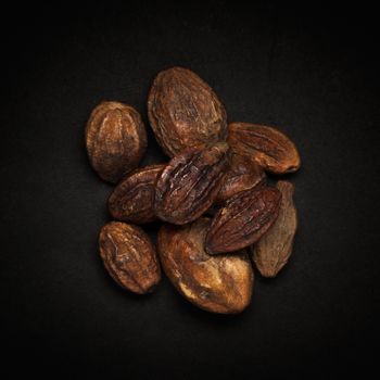 Top view of Organic Inknut or Harr (Terminalia chebula) isolated on dark background.