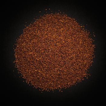 Top view of Organic Small Brown Mustard Seeds (Brassica juncea) isolated on dark background.