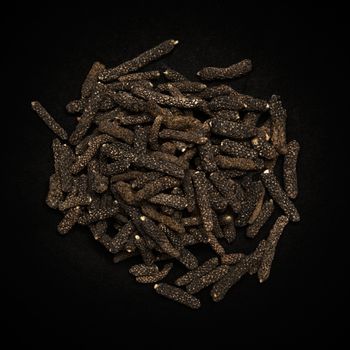 Top view of Organic Long pepper Dried Fruit (Piper longum) isolated on dark background.