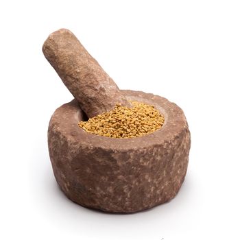 Organic Fenugreek (Trigonella foenum-graecum) in mortar with pestle, isolated on white background.