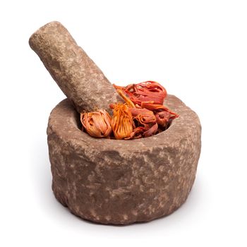 Organic Mace or jayitri (Myristica fragrans) in mortar with pestle, isolated on white background.