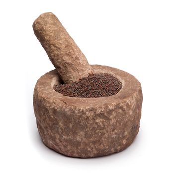 Organic brown mustard (Brassica juncea) in mortar with pestle, isolated on white background.