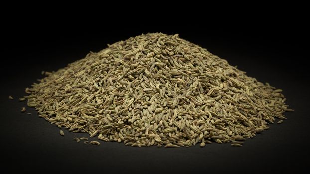Pile of Organic Aniseed (Pimpinella anisum) on dark background.