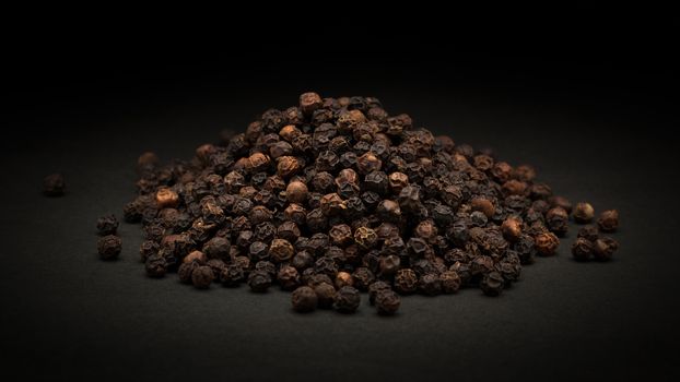 Pile of Organic Black pepper (Piper nigrum) on dark background.
